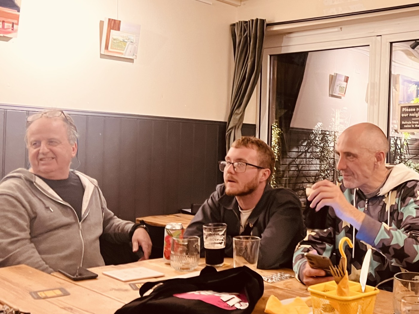 Men Talk Music members sharing drinks and a laugh around a pub table
